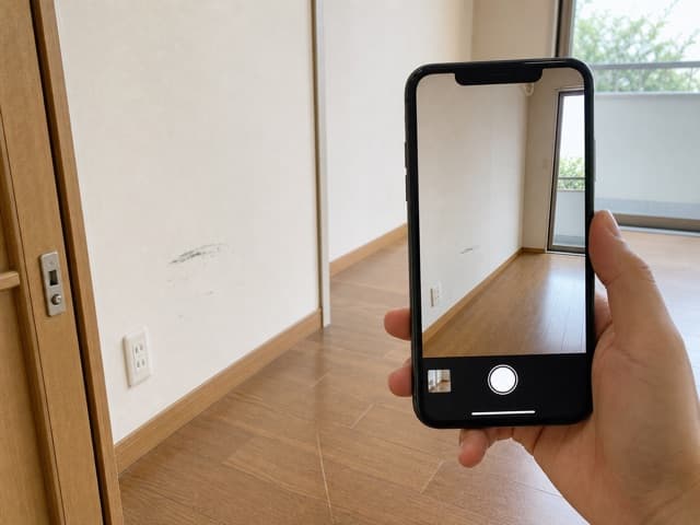 部屋の傷をスマホで撮影している様子